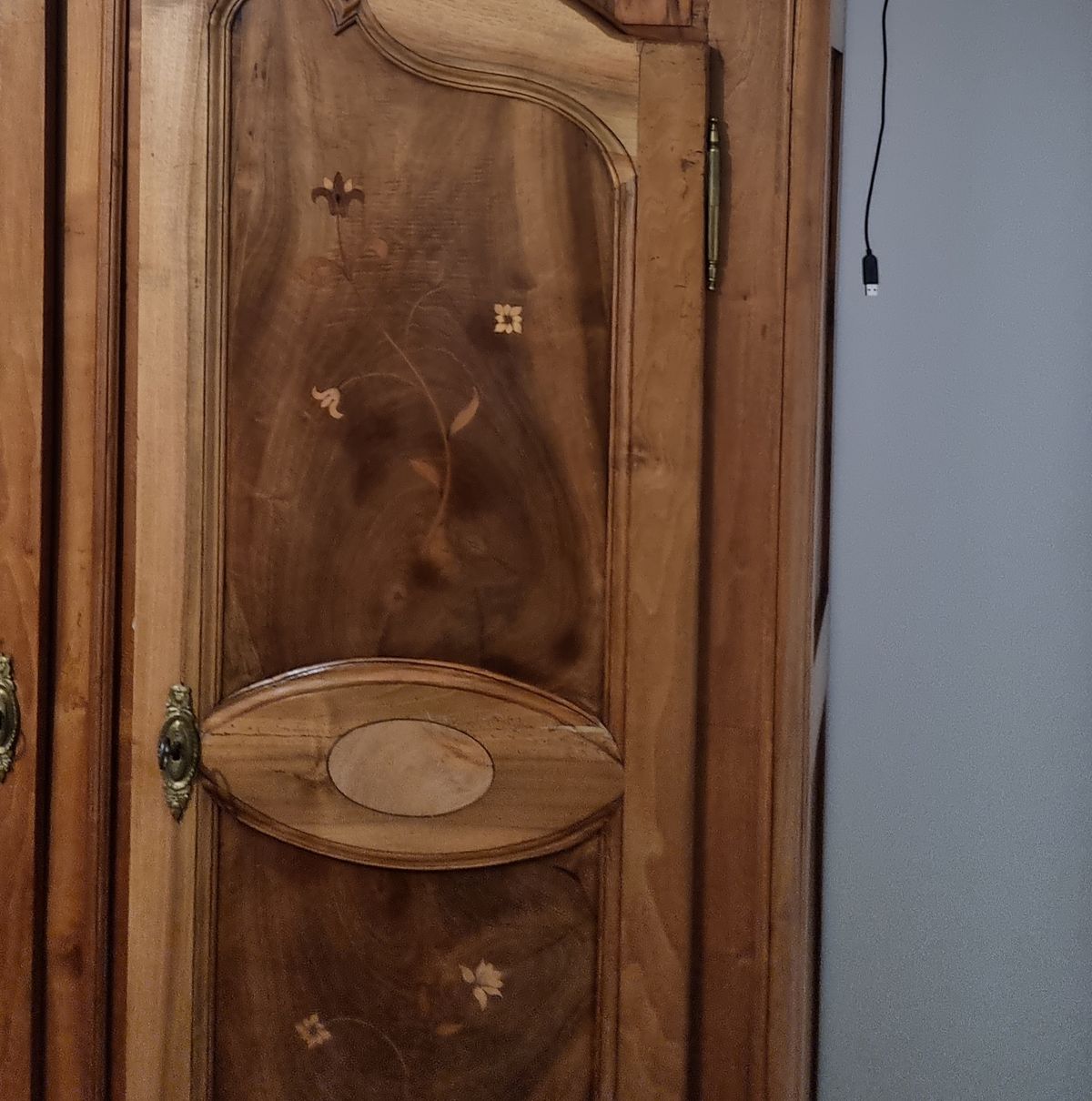 Photo of the wardrobe door with its brass lock and a charging cable hanging beside it